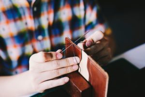 man hand stitching leather